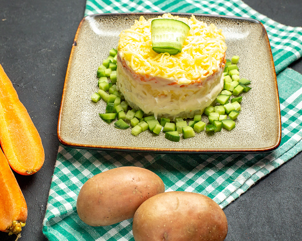 side-view-delicious-salad-served-with-chopped-cucumber-half-folded-green-stripped-towel-carrots-potatoes-dark-background